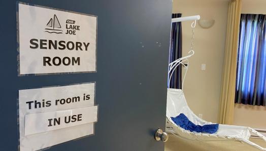 The door to the CNIB Lake Joe Multi-Sensory Room. A sign reads, “This room is in use.” There is a hanging chair inside the room.